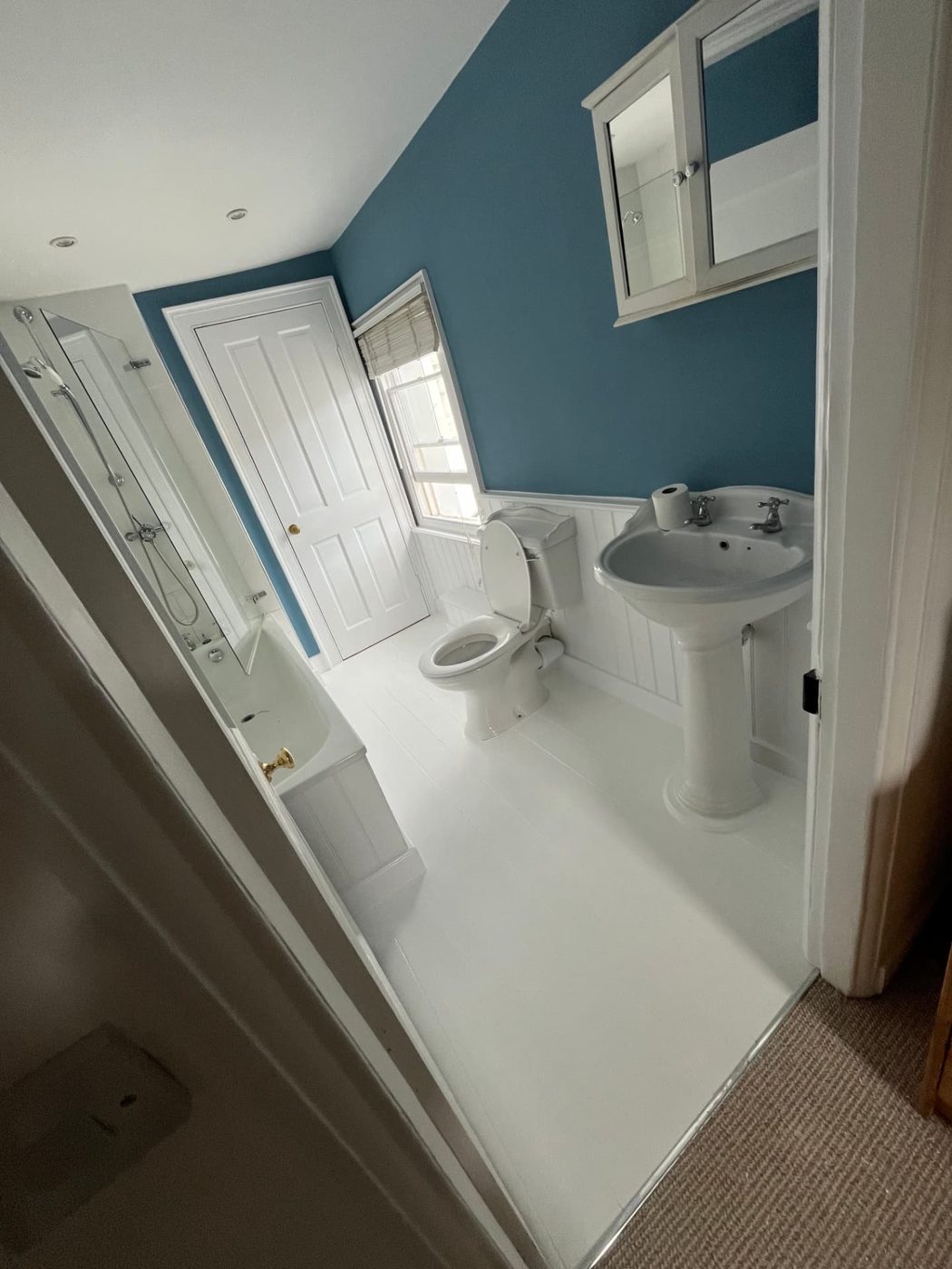 Bathroom in deep blue: A bold blue above white tongue-and-groove, with a painted white floor and woodwork.